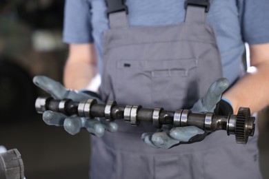 Photo of Auto part. Professional mechanic with camshaft indoors, closeup view