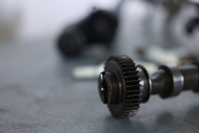 Photo of Auto part. Camshaft on grey table indoors, closeup. Space for text