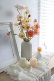 Photo of Bouquet of beautiful poppy flowers, frame and burning candles on table indoors
