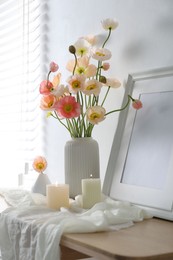Photo of Bouquet of beautiful poppy flowers, frame and burning candles on table indoors