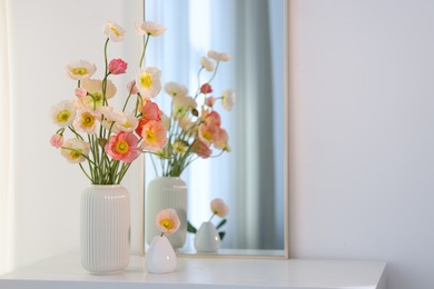 Photo of Beautiful poppy flowers and mirror on table indoors. Space for text