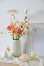 Photo of Bouquet of beautiful poppy flowers, frame and burning candles on table indoors