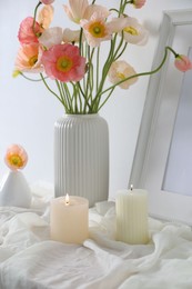 Photo of Bouquet of beautiful poppy flowers, frame and burning candles on table indoors