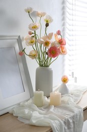 Photo of Bouquet of beautiful poppy flowers, frame and burning candles on table indoors