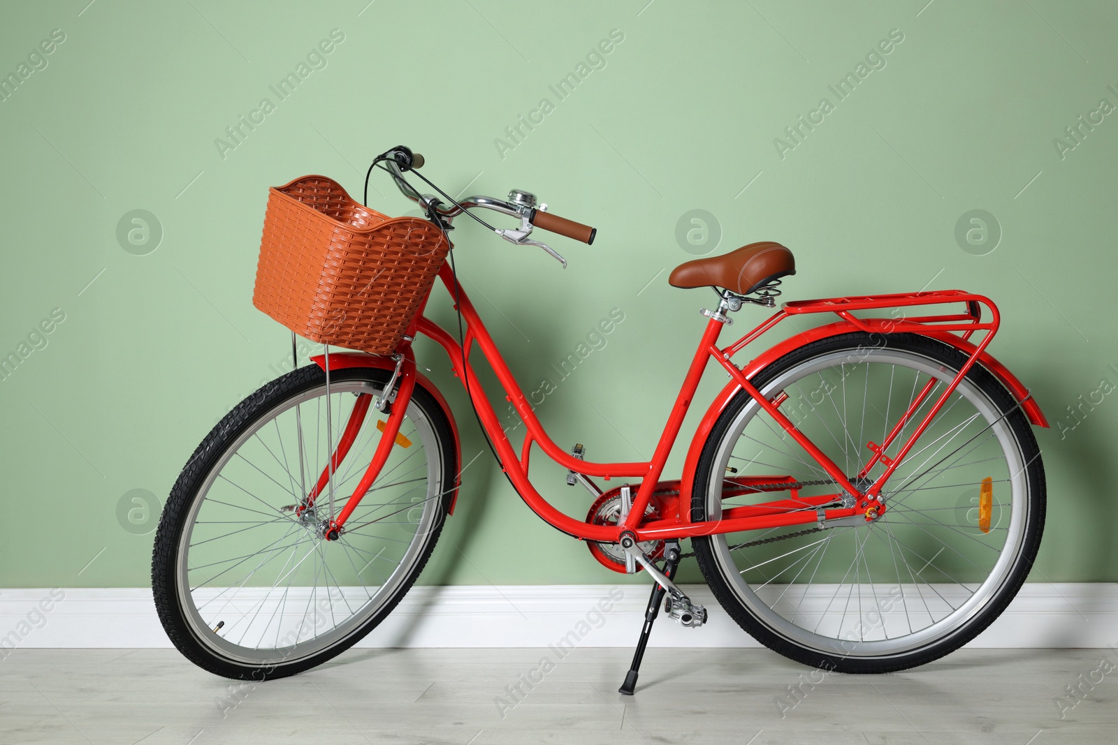 Red bicycle with basket near light green wall indoors Photo of Red bicycle with basket near light green wall indoors
