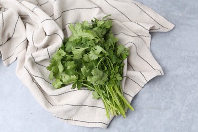 Photo of Fresh aromatic cilantro and towel on light grey table, top view