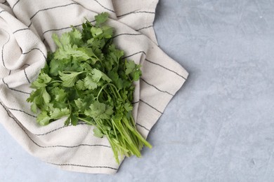 Photo of Fresh aromatic cilantro and towel on light grey table, top view. Space for text