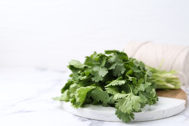 Photo of Fresh aromatic cilantro, cutting board and thread on white marble table, closeup. Space for text