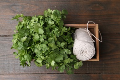 Photo of Fresh aromatic cilantro and thread in crate on wooden table, top view