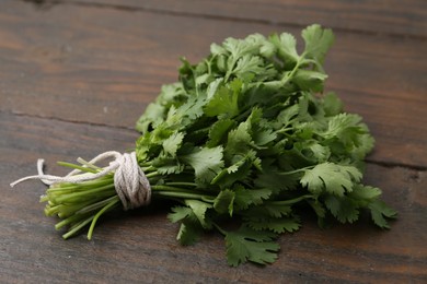 Photo of Bunch of fresh aromatic cilantro on wooden table, closeup