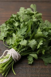 Photo of Bunch of fresh aromatic cilantro on wooden table, closeup