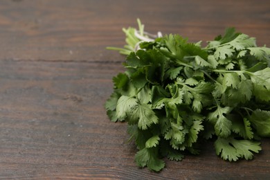 Photo of Bunch of fresh aromatic cilantro on wooden table, closeup. Space for text