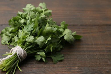 Photo of Bunch of fresh aromatic cilantro on wooden table, closeup. Space for text