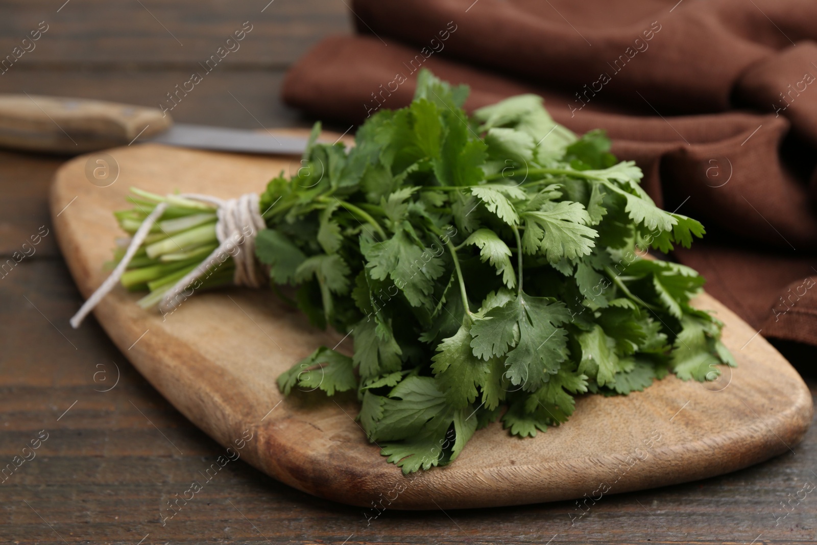 Cutting board with fresh cilantro and knife on wooden table, closeup Photo of Cutting board with fresh cilantro and knife on wooden table, closeup
