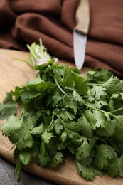Photo of Cutting board with fresh cilantro and knife on wooden table, closeup