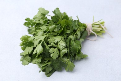 Photo of Bunch of fresh aromatic cilantro on white table, closeup
