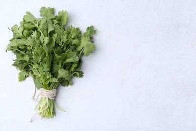 Photo of Bunch of fresh aromatic cilantro on white table, top view. Space for text