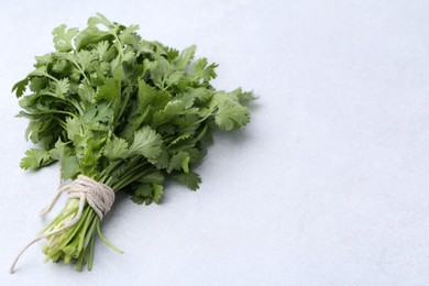 Photo of Bunch of fresh aromatic cilantro on white table. Space for text