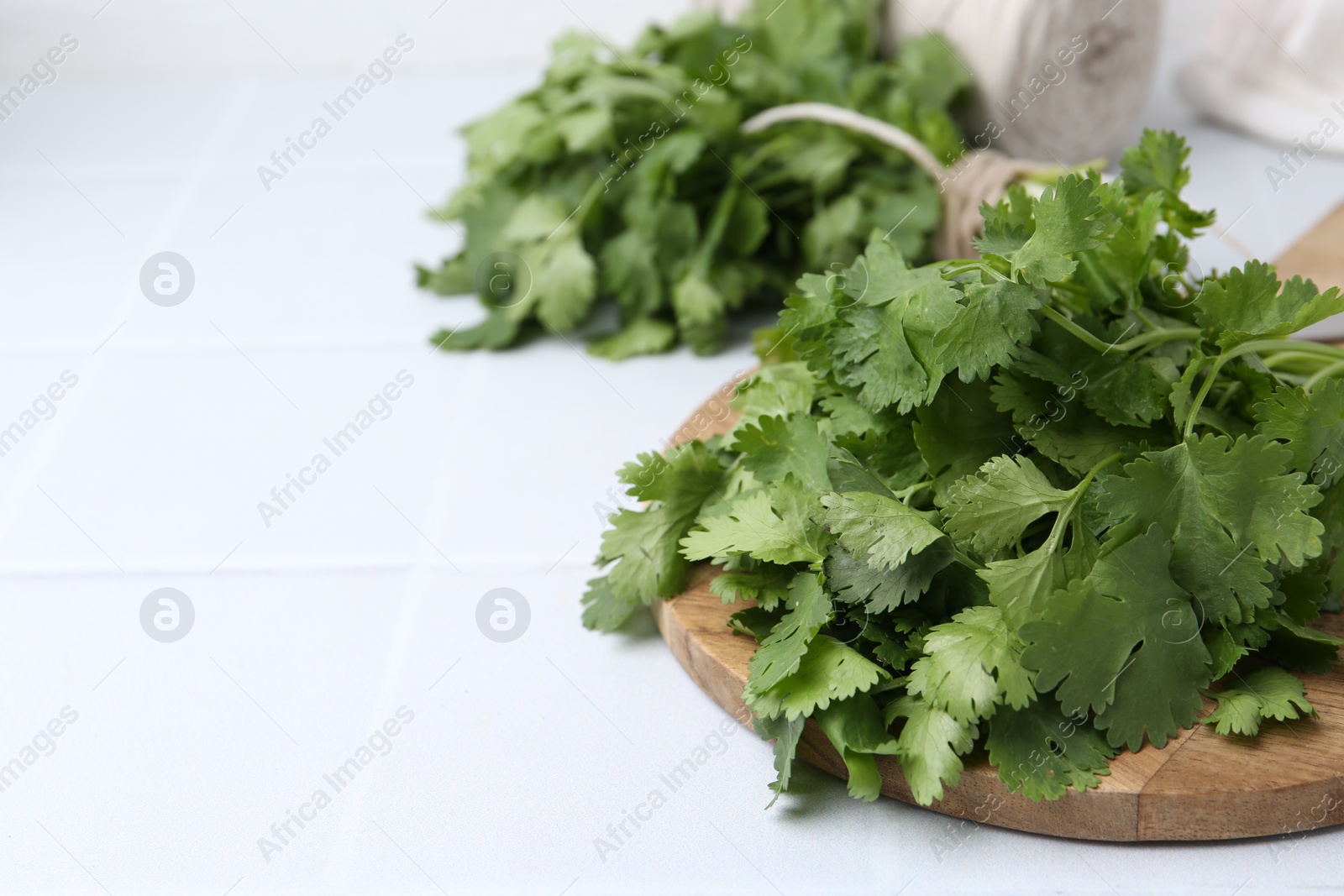 Bunch of fresh aromatic cilantro on white table, closeup. Space for text Photo of Bunch of fresh aromatic cilantro on white table, closeup. Space for text