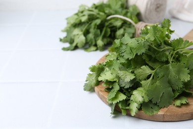 Photo of Bunch of fresh aromatic cilantro on white table, closeup. Space for text