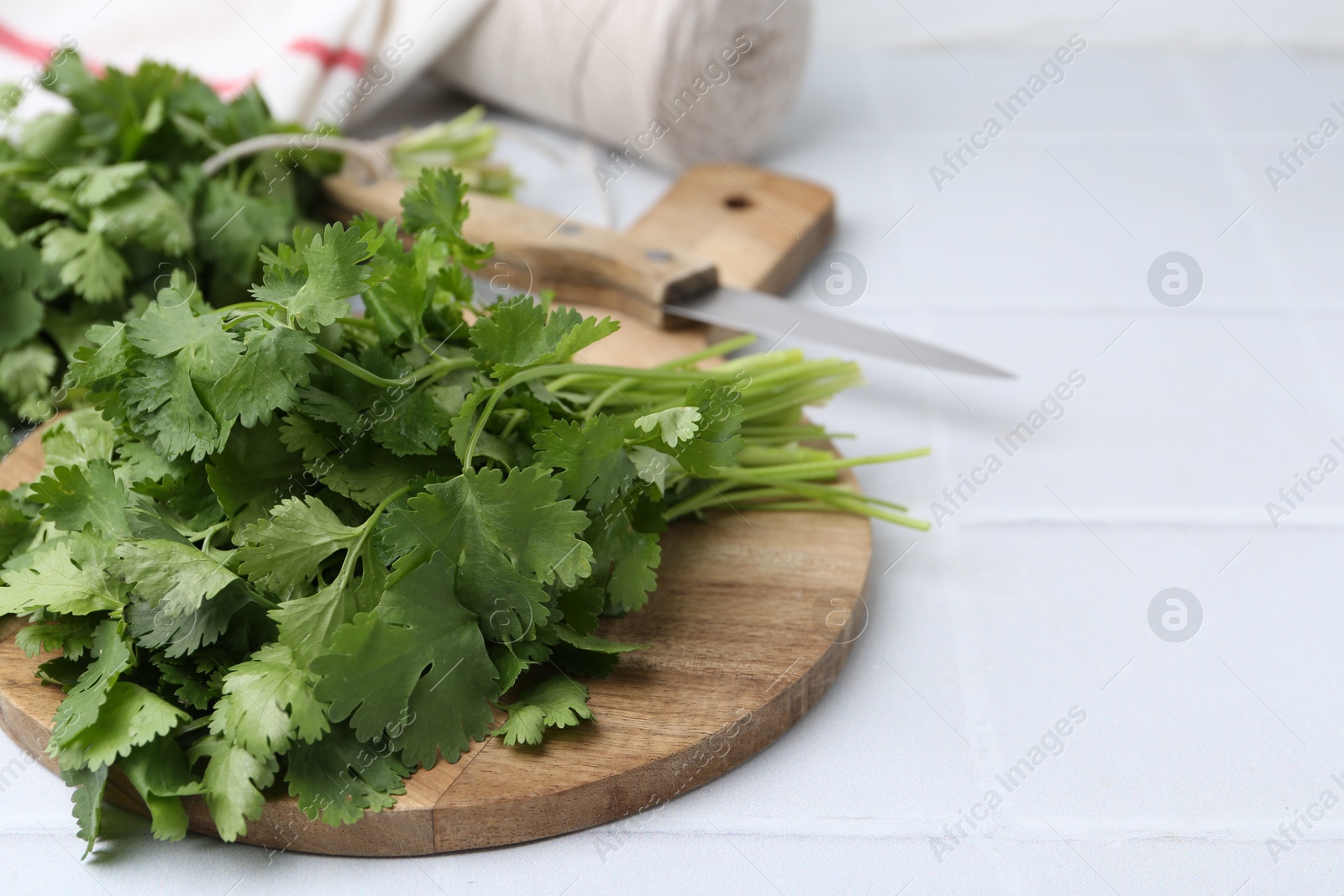 Cutting board with fresh cilantro and knife on white tiled table, closeup. Space for text Photo of Cutting board with fresh cilantro and knife on white tiled table, closeup. Space for text