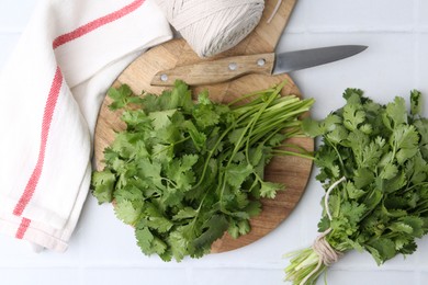 Photo of Cutting board with fresh cilantro and knife on white table, flat lay