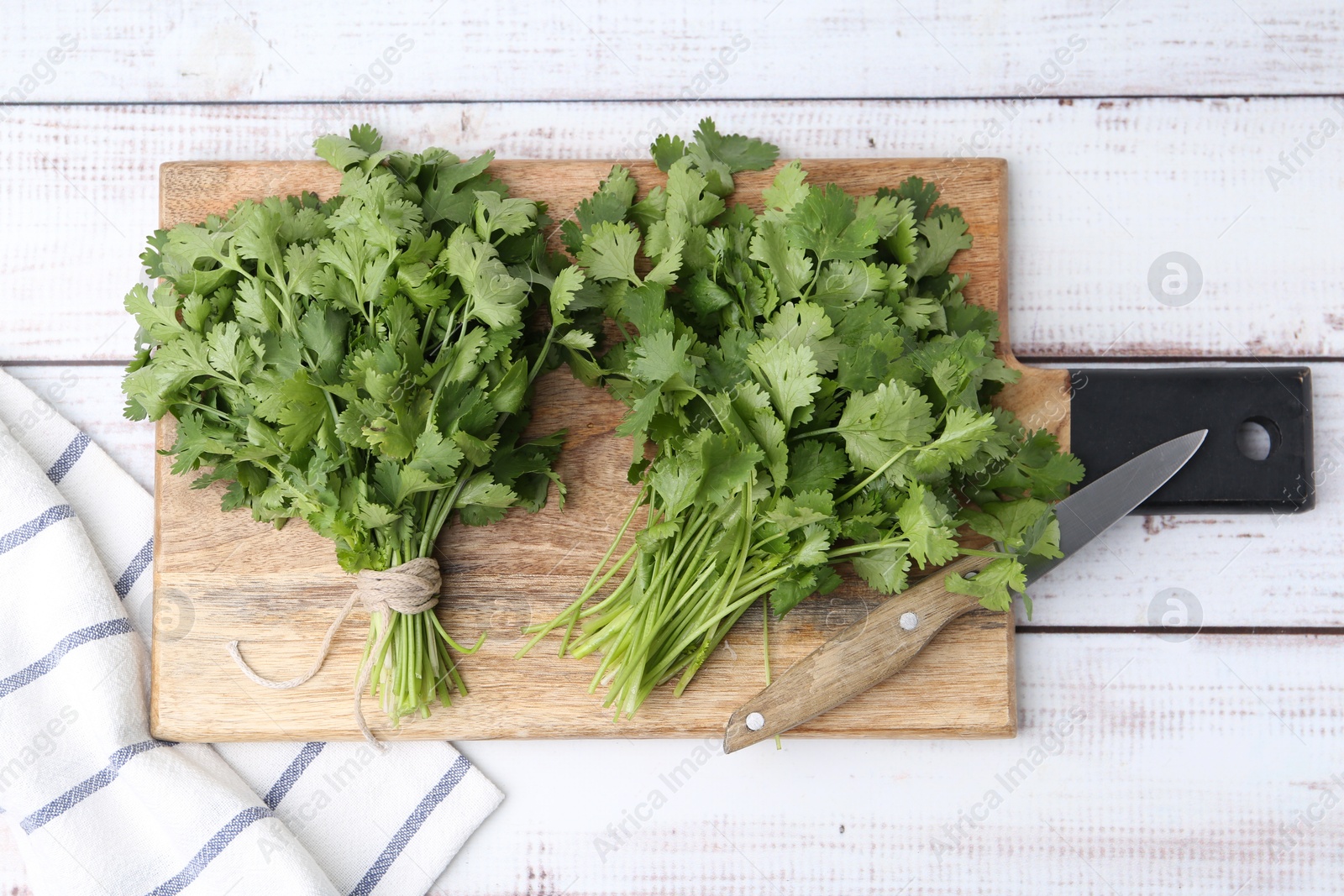 Cutting board with fresh cilantro and knife on white wooden table, top view Photo of Cutting board with fresh cilantro and knife on white wooden table, top view