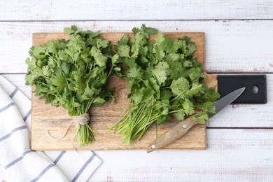Photo of Cutting board with fresh cilantro and knife on white wooden table, top view