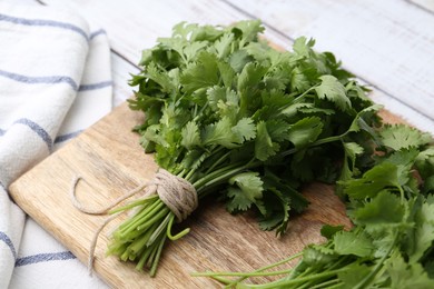 Photo of Bunch of fresh aromatic cilantro on white wooden table, closeup