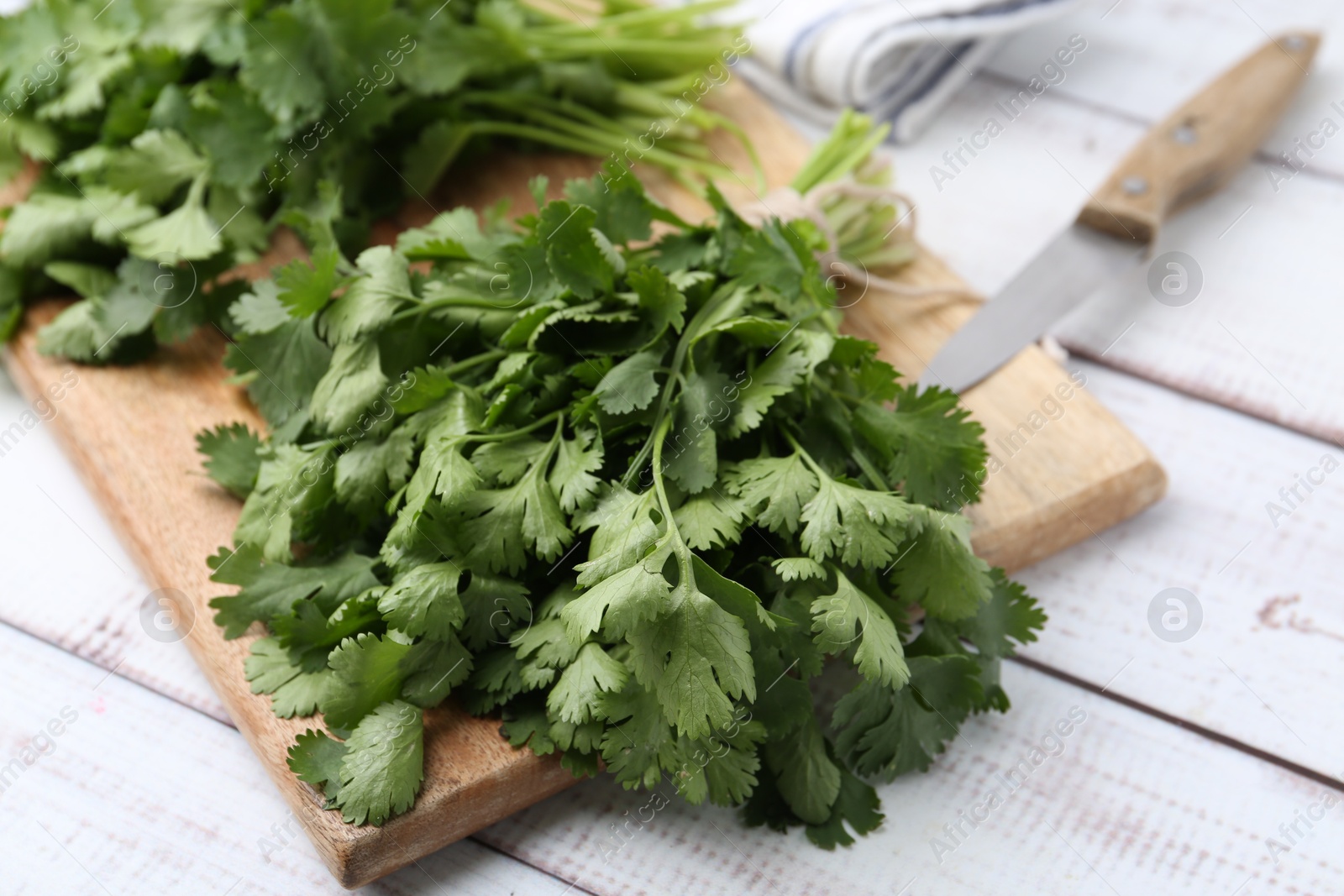 Cutting board with fresh cilantro and knife on white wooden table, closeup Photo of Cutting board with fresh cilantro and knife on white wooden table, closeup