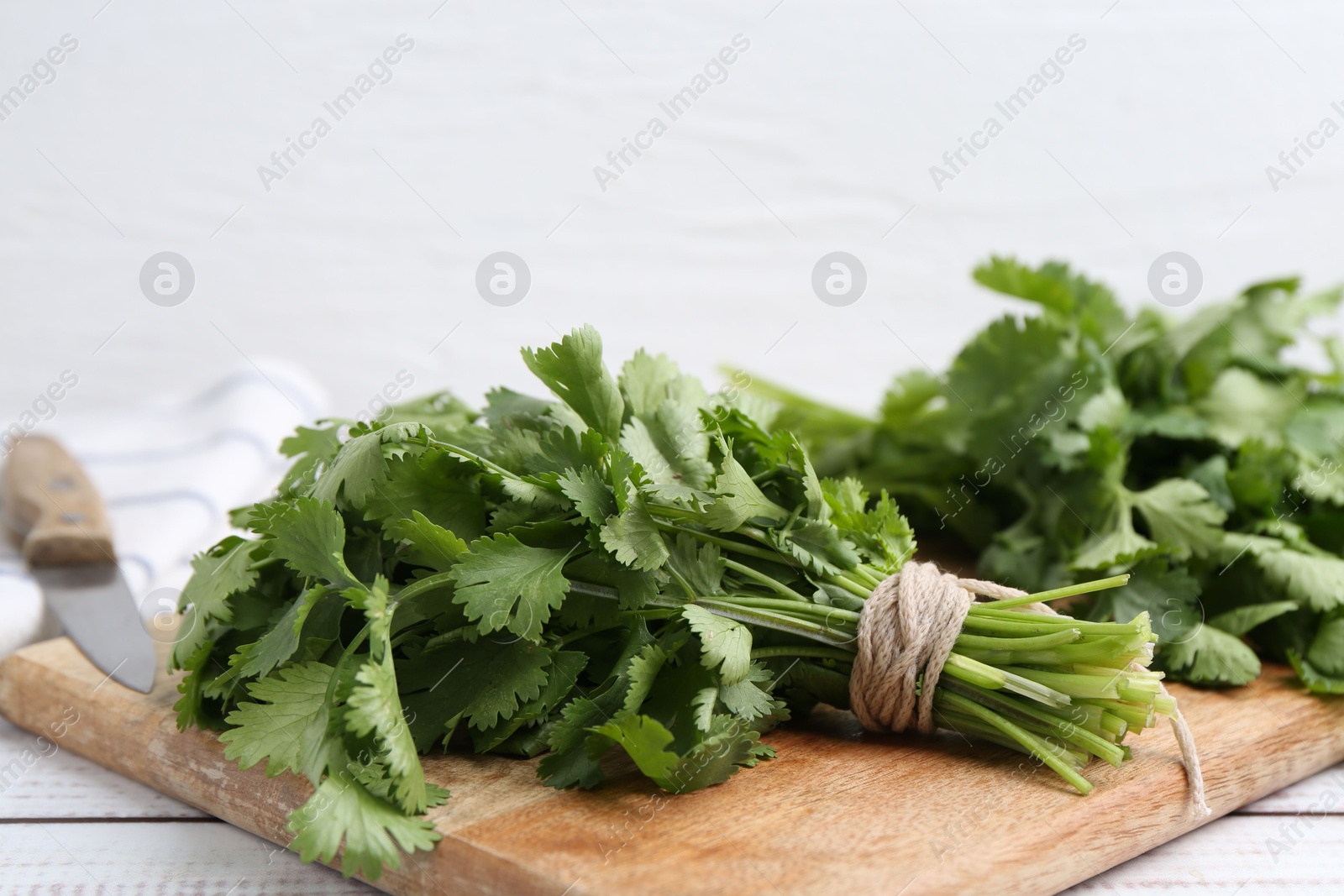 Cutting board with fresh cilantro and knife on white wooden table, closeup. Space for text Photo of Cutting board with fresh cilantro and knife on white wooden table, closeup. Space for text