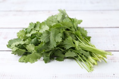 Photo of Fresh aromatic cilantro on white wooden table, closeup