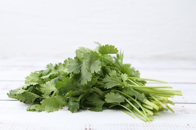 Photo of Fresh aromatic cilantro on white wooden table, closeup