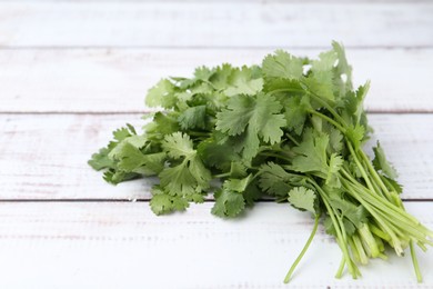 Photo of Fresh aromatic cilantro on white wooden table, closeup