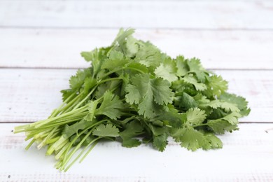 Photo of Fresh aromatic cilantro on white wooden table, closeup