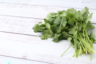 Photo of Fresh aromatic cilantro on white wooden table, closeup. Space for text