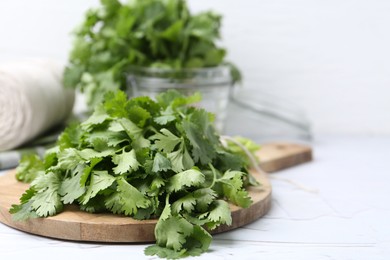 Photo of Fresh aromatic cilantro on white table, closeup. Space for text