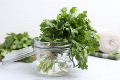 Photo of Fresh aromatic cilantro in jar on white table, closeup