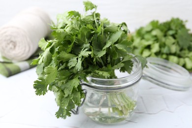 Photo of Fresh aromatic cilantro in jar on white table, closeup