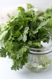 Photo of Fresh aromatic cilantro in jar on white table, closeup