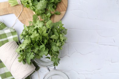 Photo of Fresh aromatic cilantro in jar on white table, flat lay. Space for text