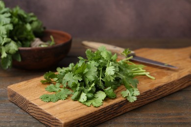Photo of Cutting board with fresh cilantro and knife on wooden table