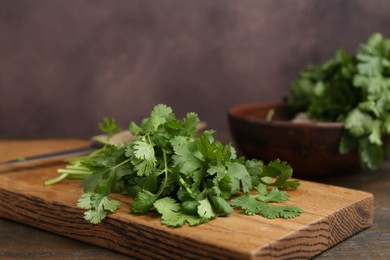 Photo of Cutting board with fresh cilantro and knife on wooden table, closeup. Space for text