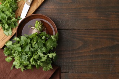 Photo of Cutting board with fresh cilantro and knife on wooden table, flat lay. Space for text