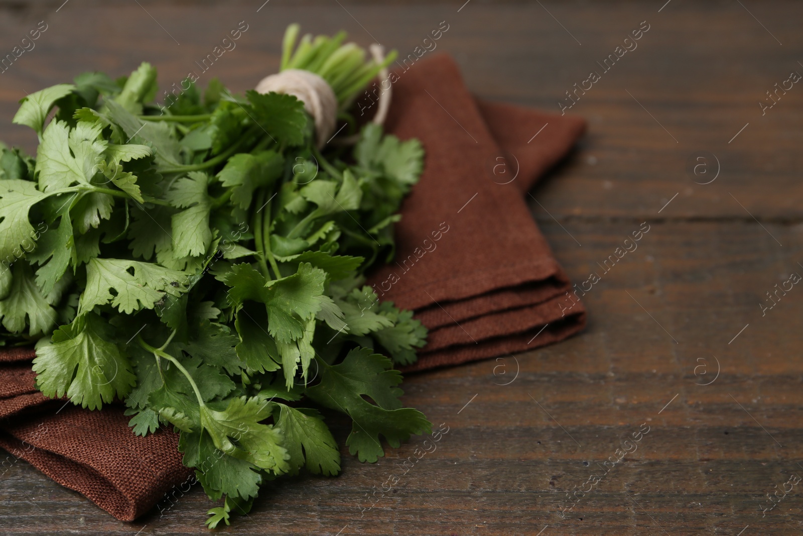 Photo of Fresh aromatic cilantro on wooden table, closeup. Space for text