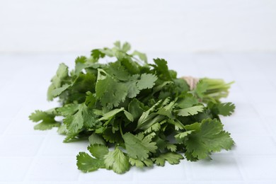 Photo of Fresh aromatic cilantro on white tiled table, closeup