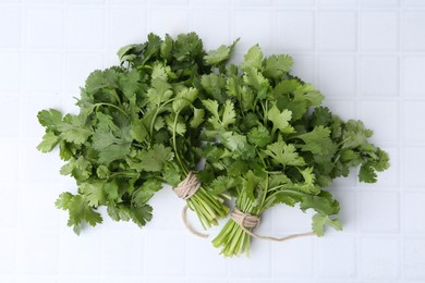 Photo of Fresh aromatic cilantro on white tiled table, top view