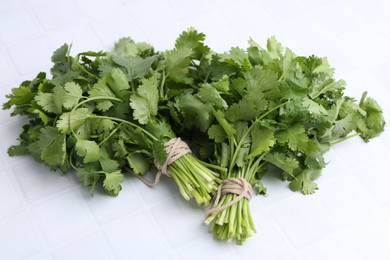 Photo of Fresh aromatic cilantro on white tiled table, closeup