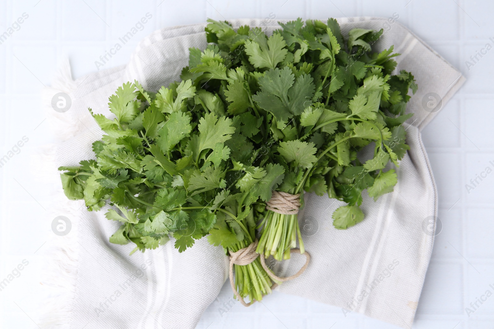 Photo of Fresh aromatic cilantro on white tiled table, top view