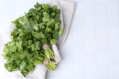 Photo of Fresh aromatic cilantro on white tiled table, top view. Space for text